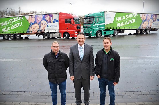 Christoph Blanke, Prof. Dr. J&ouml;rg Wagner und Marcus Otto pr&auml;sentieren zwei der insgesamt vier LKW mit Hochschulwerbung (Foto: Tina Bergknapp)