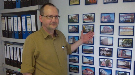 Ulf Zaspel in seinem B&uuml;ro vor der Wand mit Sehensw&uuml;rdigkeiten von St&auml;dten, die er per Video pr&auml;sentiert (Foto: Kurt Frank)
