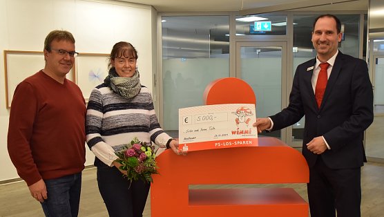 Stellvertretender Filialleiter der Hauptstelle Ingo Wolf &uuml;berreicht den gl&uuml;cklichen Gewinnern einen symbolischen Scheck und Blumen. (Foto: V.Angelstein)