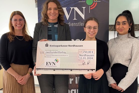 Jana Z&ouml;ller &uuml;bergibt einen Spendenscheck in H&ouml;he von 250 Euro an die stellvertretende Schulleiterin der Grund- und Regelschule K&auml;the Kollwitz, Stephanie R&ouml;mer (links), und die beiden Sch&uuml;lersprecherinnen Emilia Kiel und Mursal Masoud. (Foto: EVN)