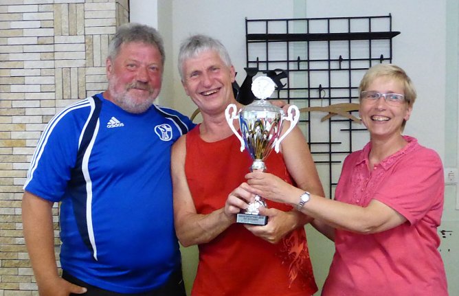 Strahlend nimmt Uwe Schm&ouml;gner von NSV-Kegelabteilungsleiterin Heike Fiedler den Siegerpokal in Empfang. Daneben der Einzelbeste Reiner Hagemeier. (Foto: Uwe Tittel)