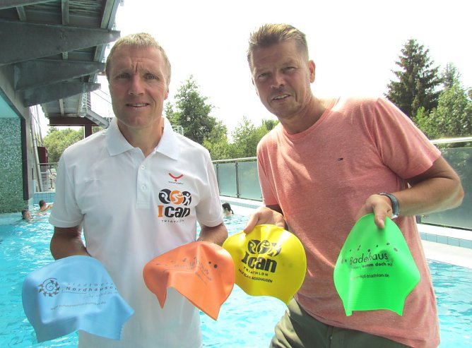 Renndirektor des ICAN Nordhausen, Ulrich Konschak, und Gesch&auml;ftsf&uuml;hrer der Badehaus Nordhausen GmbH, Jens Eisenschmidt, pr&auml;sentierten auch in diesem Jahr wieder die neu gestalteten Badekappen f&uuml;r die Athleten des Scheunenhof- und ICAN-Triathlons am kommenden Wochenende. (Foto: Stadtwerke Nordhausen)