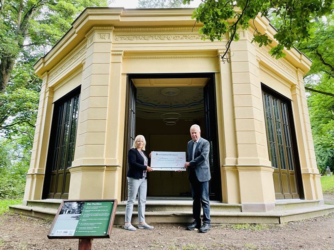 Ehrenvorsitzender des NUV, Hans-Joachim Junker, bei der symbolischen Scheck&uuml;bergabe an Hannelore Haase, Vorsitzende F&ouml;rderverein Park Hohenrode, am neu renovierten Pavillon (Foto: Claudia Rheinl&auml;nder)
