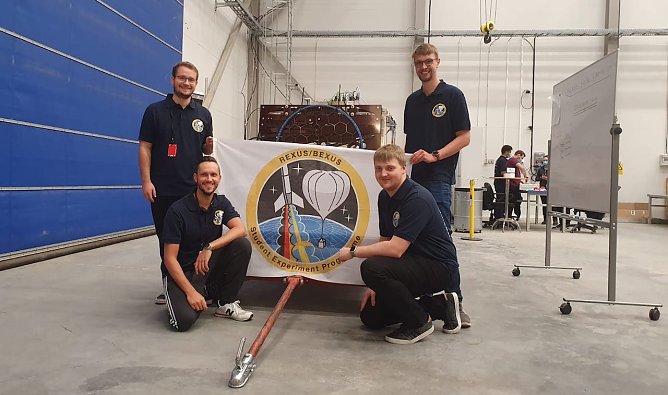 Das Foto zeigt die Studierenden J. Stephan, D. Bochmann, J. Jelonek und L. Gebken in Esrange an der Gondel mit den montierten Experimenten, im Hintergrund die Messspule mit Scherenarm zum Absenken der Spule nach dem Ballonstart.  (Foto: Torsten Lutz)