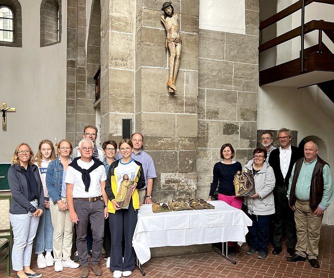 Die Gemeinde freut sich, das Kruzifix wieder in der Kirche zu wissen. B&auml;rbel Treutler vom Gemeindekirchenrat h&auml;lt die restaurierte Altartafel in H&auml;nden, die damals ebenfalls zerbrochen ist. Pfarrer Klemens M&uuml;ller (im Anzug) steht rechts neben ihr. Den Vorsitzenden des Gemeindekirchenrates, Ralf Schumann, finden Sie links neben dem Tisch, hinten im hellblauen Hemd (Foto: Steffen Mund)