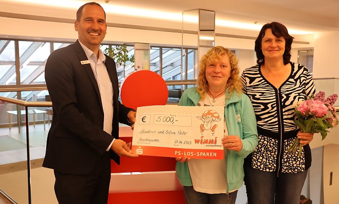 Stellvertretender Filialleiter Ingo Wolf &uuml;berreicht den gl&uuml;cklichen Gewinnern einen symbolischen Scheck und Blumen. (Foto: KSK)